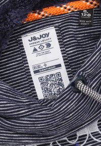 Marineblauwe en witte gestreepte stof, met een luxe donkere voering, voorzien van een merketiket, QR-code en oranje accent. Bevat trekkoordhardware.