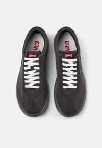 Dunkelgraue Sneaker mit weißen Schnürsenkeln, ausgestattet mit einem glatten Obermaterial aus Stoff und einer Gummisohle. Auffälliges rotes Logo-Tag auf der Zunge.