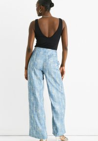 Black tank top with a deep V-back, paired with light blue wide-leg pants featuring a textured, faded pattern.