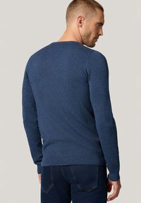 Niebieski sweter z dzianiny z długimi rękawami, okrągłym dekoltem, ściągaczami przy mankietach i dolnej krawędzi. Tekstura wydaje się gładka z delikatnym wzorem.