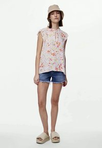 Αμάνικο τοπ με φλοράλ σχέδιο σε ανοιχτό ροζ χρώμα, με ριγέ μανίκια, συνδυασμένο με τζιν σορτσάκια και μπεζ πλατφόρμες.