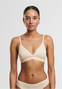 Soft beige bralette featuring a triangular design, thin adjustable straps, a wide underband, and a smooth texture for comfort.