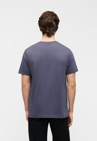 Ανδρική κοντομάνικη μπλούζα σε σκούρο γκρι βαμβάκι με κλασικό λαιμόκοψη, λεία υφή και μινιμαλιστικό σχεδιασμό.