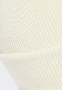 Krémová rebrová pletenina s jemnou textúrou a prehnutým okrajom. Vzor obsahuje vertikálne pruhy cez povrch.