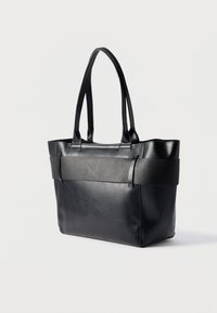 Μαύρη δερμάτινη τσάντα tote με λείο και υφή επιφάνειας. Διαθέτει δύο στιβαρές λαβές και οριζόντια διακοσμητική λωρίδα. Ορθογώνιο σχήμα.
