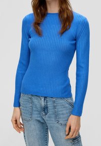 Top lungo a maniche lunghe blu a coste realizzato in tessuto elasticizzato, con scollo a cerchio e silhouette aderente, abbinato a jeans di un blu chiaro.