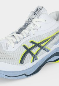 Άσπρο και γκρι παπούτσι για τρέξιμο Asics με νεον κίτρινες λεπτομέρειες, επάνω μέρος από δίχτυ και μαλακή σόλα, εμφανιζόμενο από τη πλευρά.