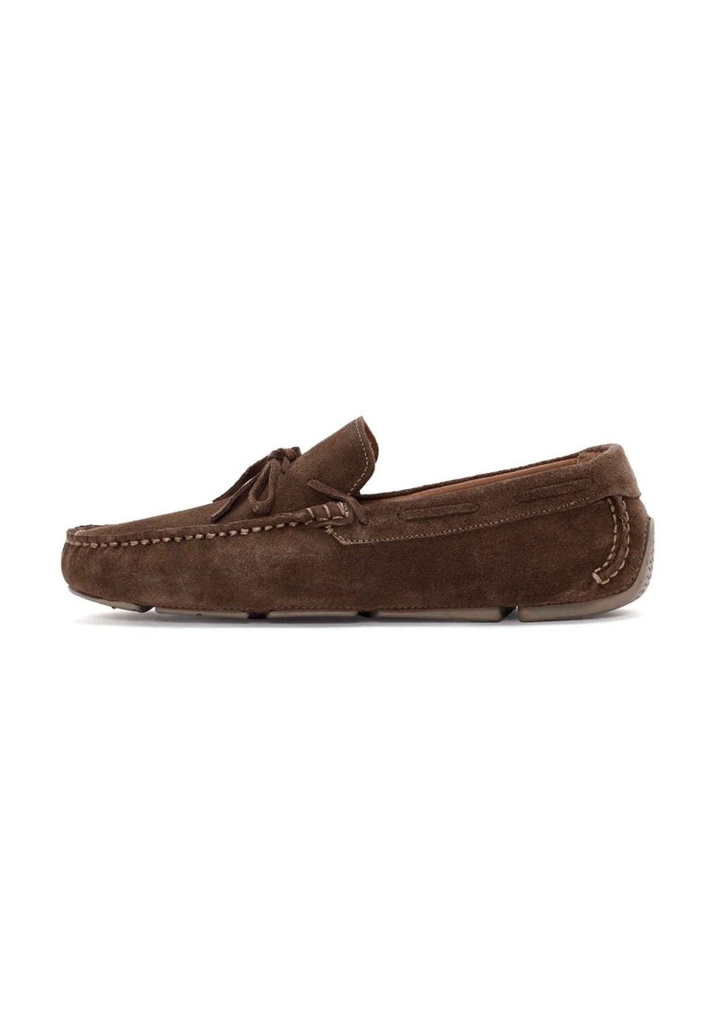 Mocasines de ante marrón con costura al estilo mocasín, suela plana y un lazo decorativo en la parte delantera. Punta redondeada y textura suave.