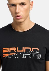 Sort bomulds T-shirt med fed orange og grå tekstdesign. Udelægningen er rund, og stoffet ser glat og tætsiddende ud.