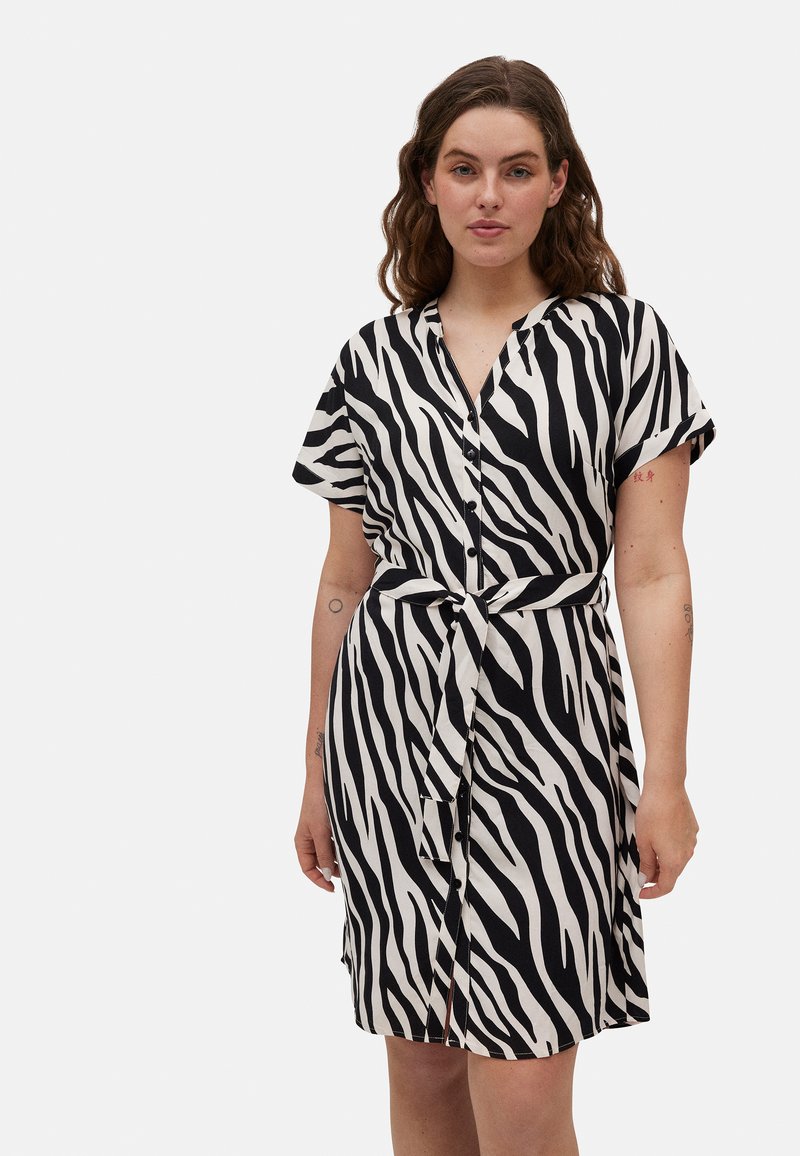 Vestido de estampado de cebra con rayas blancas y negras, mangas cortas, escote en V, cierre de botones en el frente y un lazo en la cintura. Tejido suave.