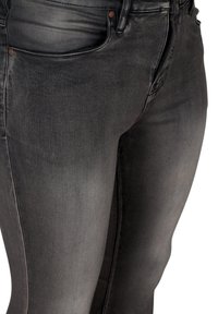 Jeans de mezclilla negra con ajuste slim, que presentan una textura suave, bolsillos delanteros y un ligero desvanecimiento para un aspecto desgastado.