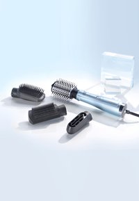 Electric blue hair styling tool with round brush attachment and three additional black brush and nozzle accessories on a white surface.