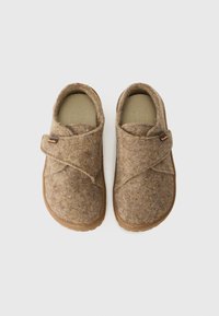 Cítiť slip-on topánky s hnedým textúrovaným zvrškom, prekrývajúcim dizajnom a hnedou gumovou podrážkou. Obsahuje prišité značkové označenie.