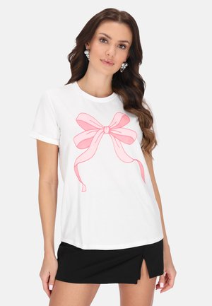 Hvid bomulds T-shirt med et stort rosa sløjfe graphic på fronten. Korte ærmer og afslappet pasform, sammen med en sort nederdel.