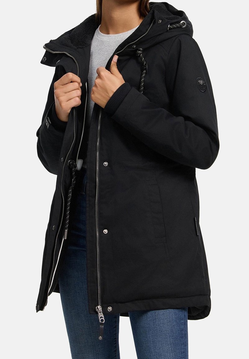Parka noire avec capuche doublée en polaire, fermeture éclair à l'avant, boutons-pression, poches latérales et poignets côtelés. Tissu globalement lisse.