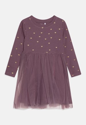 Lila Kleid mit langen Ärmeln, goldenen Herzmustern am Oberteil und einem transparenten Tüllrock als Überlagerung.