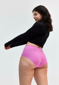 Højtsiddende pink trusser lavet af glat stof, parret med en sort tætsiddende langærmet top. Har et enkelt design og sømløse kanter.