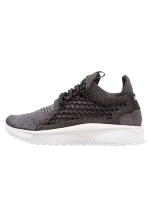 Schwarzer und grauer gestrickter Sportschuh mit wabenförmigem Mesh an den Seiten, weißer strukturierter Sohle und Zuglasche an der Ferse.