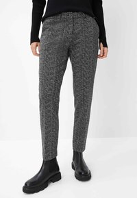 Graue Fischgrat-Hosen mit strukturiertem Finish, mit Knopfverschluss, seitlichen Taschen und schmalem Bein-Design, kombiniert mit schwarzen Knöchelstiefeln.