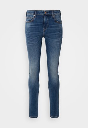 Slim-fit farkut tummansinisestä farkkukankaasta. Ominaisuuksiin kuuluu viisi taskua, vyölenkki ja kevyt haalistus. Ompeleet kontrastivärisellä vaaleanruskealla langalla.