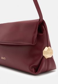 Bordeaux leren handtas met opklapbare flap, gouden geometrische sluiting, merkglogo "Liu Jo" in goud op de voorhoed.