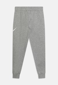 Vaaleanharmaat Nike-housut, joissa on joustava vyötärö ja lahkeensuut, ja vasemmassa reidessä pieni valkoinen swoosh-logo.