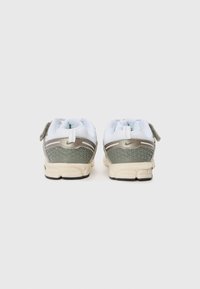Leichte Sportschuhe in Grün und Weiß mit einem strukturierten Rücken, ausgestattet mit einer gemusterten Sohle und reflektierenden Akzenten. Rückansicht.