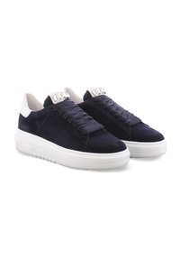 Marineblaue Wildledersneaker mit weißen Akzenten, ausgestattet mit dicken Schnürsenkeln und einer flachen Gummisohle. Ein bemerkenswertes Detail ist ein dekoratives metallisches Element auf der Zunge.