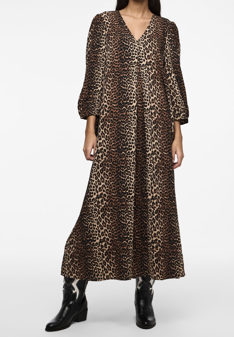 Maxi vestido de estampado de leopardo, escote en V, mangas largas y abullonadas, silueta fluida, tejido texturizado, combinado con botas de cowboy negras.