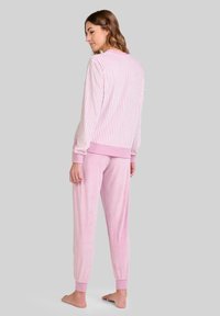 Top de manga larga a rayas rosas con puños acanalados, combinado con joggers de tela suave en color rosa sólido, con tobillos elásticos.