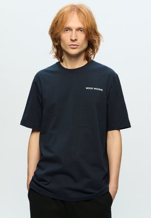 Marinblå bomull t-shirt med korta ärmar, rund hals, och vitt broderat "WOOD WOOD"-logotyp på vänster bröst, med en avslappnad passform.