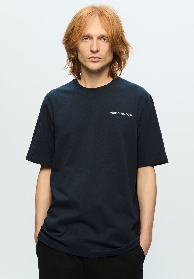 Mørkeblå bomulds t-shirt med korte ærmer, rund hals og hvidt broderet "WOOD WOOD" logo på venstre bryst, med en afslappet pasform.