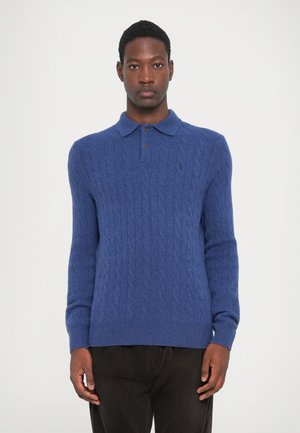 Pull en maille torsadée bleu avec un col polo, deux boutons, des poignets et un ourlet côtelés. Petit logo sur le côté gauche de la poitrine.
