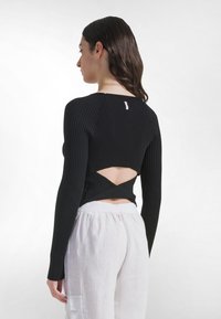 Schwarzes, geripptes Langarmshirt mit Kreuzrücken-Design. Figurbetonte Passform mit einem dezenten Logo im oberen Rückenbereich und strukturierter Stoff.