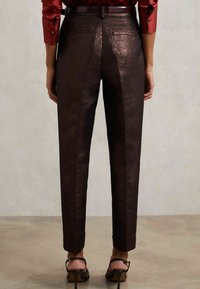 Ruskeat, kiiltävät, kapenevat housut, joissa on sileä kangas, takataskut ja rullatut lahkeet, yhdistettynä korkokengillä.