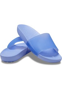 Sandales à enfiler bleu clair avec semelles texturées et larges brides translucides, disposées en croix sur un fond blanc.