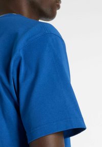 Blå bomuld T-shirt med korte ærmer og rund hals. Synlig syning langs skulder- og ærmekanter.