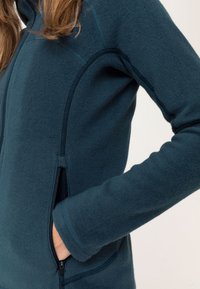 Dark teal fleece jacket featuring a zippered front, side pockets, and contrast stitching, highlighting a smooth texture and fitted design.
