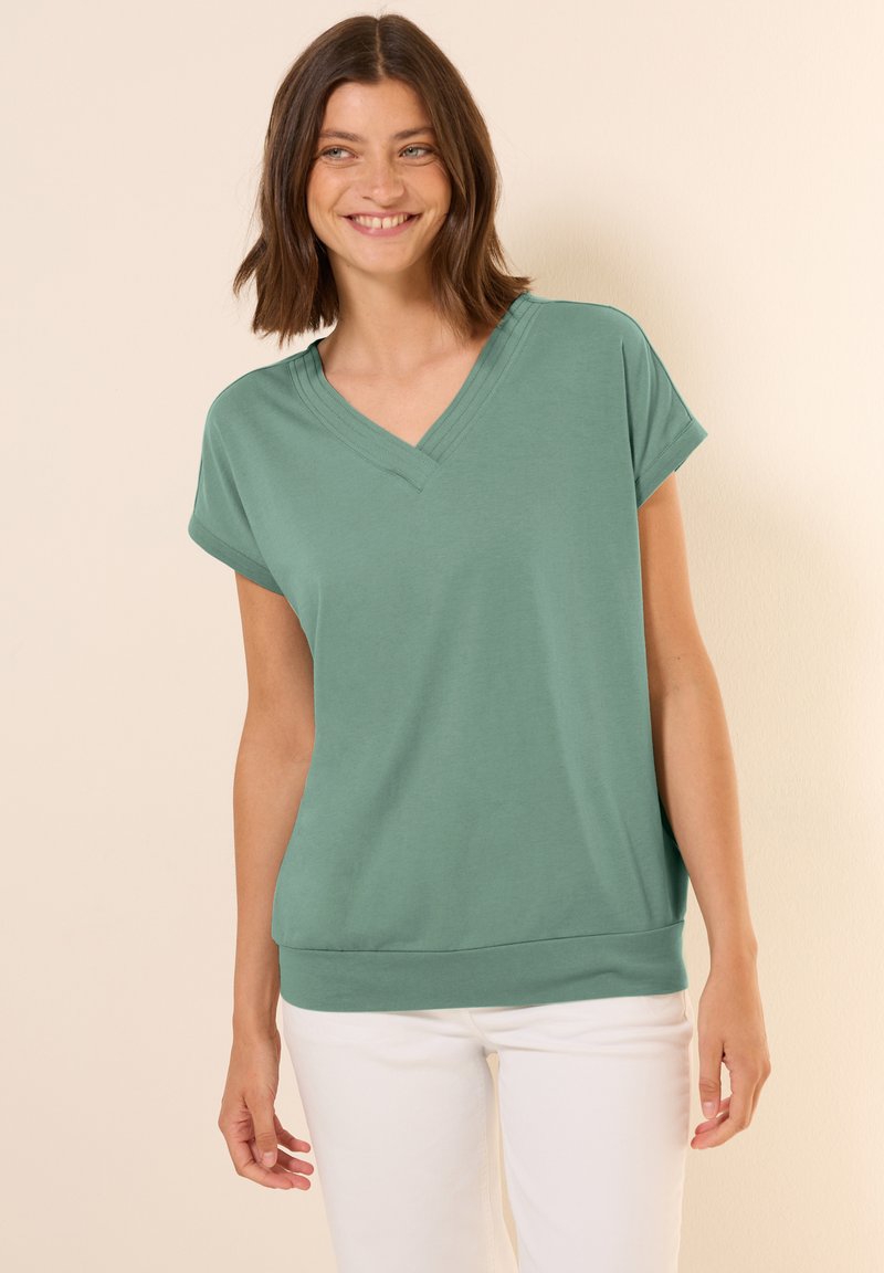 Maglietta verde a maniche corte con scollo a V e vestibilità rilassata, realizzata in tessuto morbido, con dettagli a coste sul collo e una linea dell'orlo discreta.