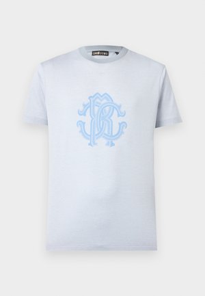 Tricou bleu deschis cu mâneci scurte și guler rotund, cu un logo mare și elaborat cu monogramă albastră, centrat pe piept.
