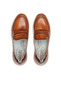 Zapatos marrones de cuero tipo slip-on con acabado liso, puntera redondeada, forro acolchado y suela de goma con pequeños studs decorativos.