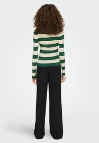 Groen en crèmekleurig gestreept ribbeltrui met lange mouwen, getailleerd in de taille, gecombineerd met zwarte wijde broek.