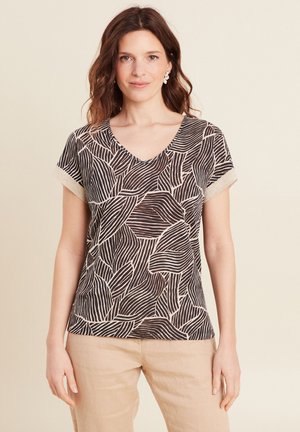 Top à manches courtes en V noir et crème avec un motif de feuilles. Dispose de manches texturées avec un léger éclat. Tissu léger.