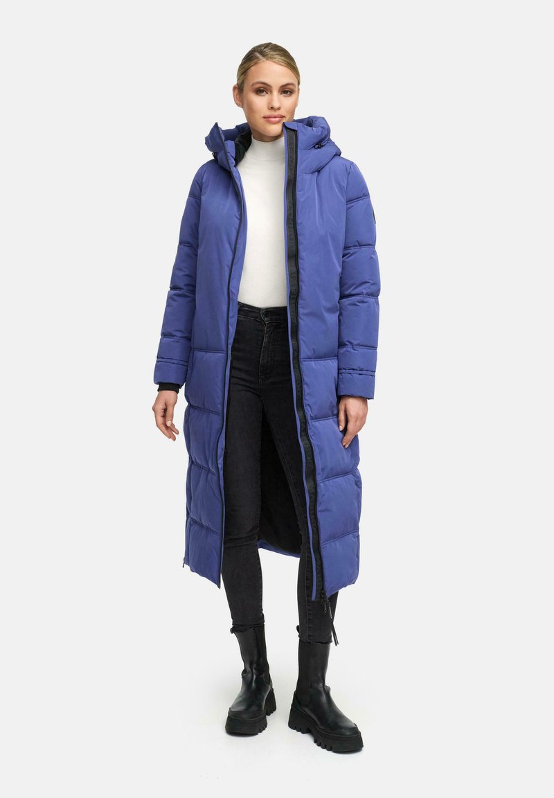 Cappotto lungo e imbottito di un vivace colore viola, con cappuccio, zip frontale e polsini elasticizzati, abbinato a pantaloni neri e stivali neri chunky.