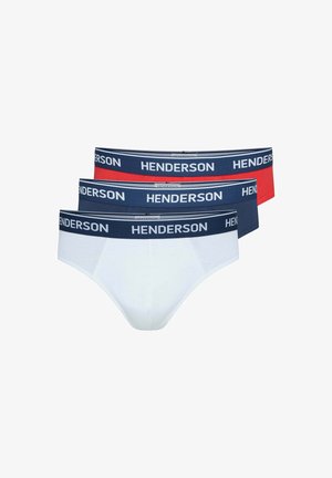 Hemdloser Mann mit kurzen lockigen Haaren, der weiße Slips mit einem dunkelblauen Bund trägt, der mit "HENDERSON" beschriftet ist, vor einfachem Hintergrund.