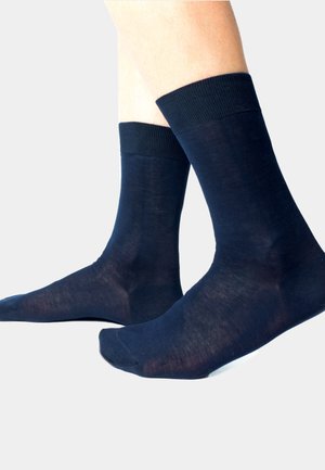 Calze blu navy realizzate in un materiale morbido ed elasticizzato. Fascette a coste e una texture liscia con un design aderente attorno al piede e alla caviglia.