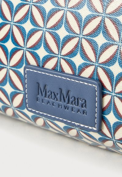 Blåt og rødt geometrisk blomsterstof med et påsyet blåt lædermærke præget med "MaxMara Beachwear."