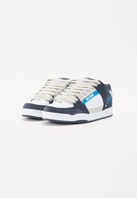 Blå og hvite sneakers laget av semsket skinn og lær, med en rund tå, fremtredende snørebånd og en logo på siden.