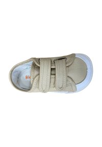 Zapato de lona beige con dos correas de velcro ajustables, suela de goma blanca y acentos cosidos. El interior presenta una marca colorida.