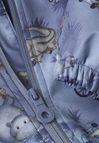 Blått tyg med tecknade dinosaurier och djur, med en grå dragkedja och samlad mudd. Materialet har en slät textur.